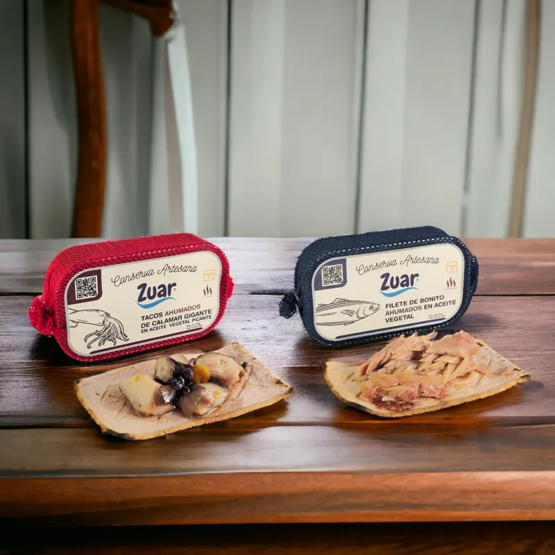 Latas de tacos ahumados de calamar gigante y de filete de bonito ahumado ZUAR, con porciones servidas sobre madera.